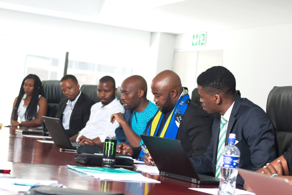 A working session around a boardroom table, laptops open, mid discussion